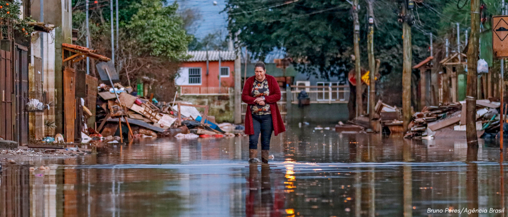 Mulher anda em rua alagada após inundação no Rio Grande do Sul